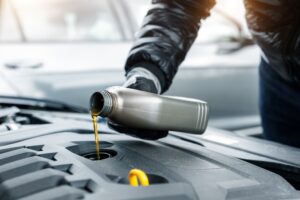 Close-up,Driver Hand Holding Small Bottle Can Pouring Synthetic Motor Oil into Car
